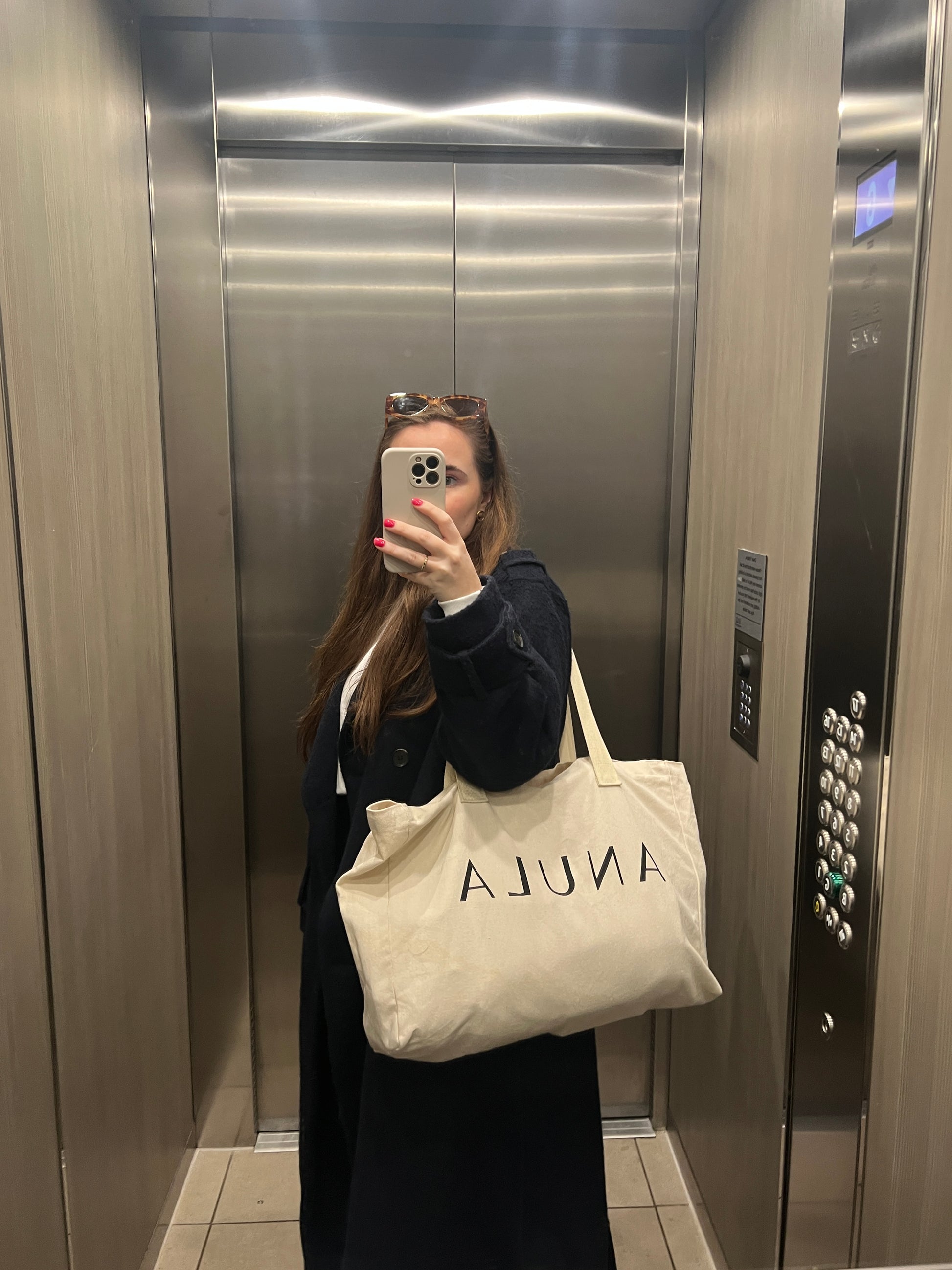 Mirror selfie - woman in lift holding ANULA tote bag